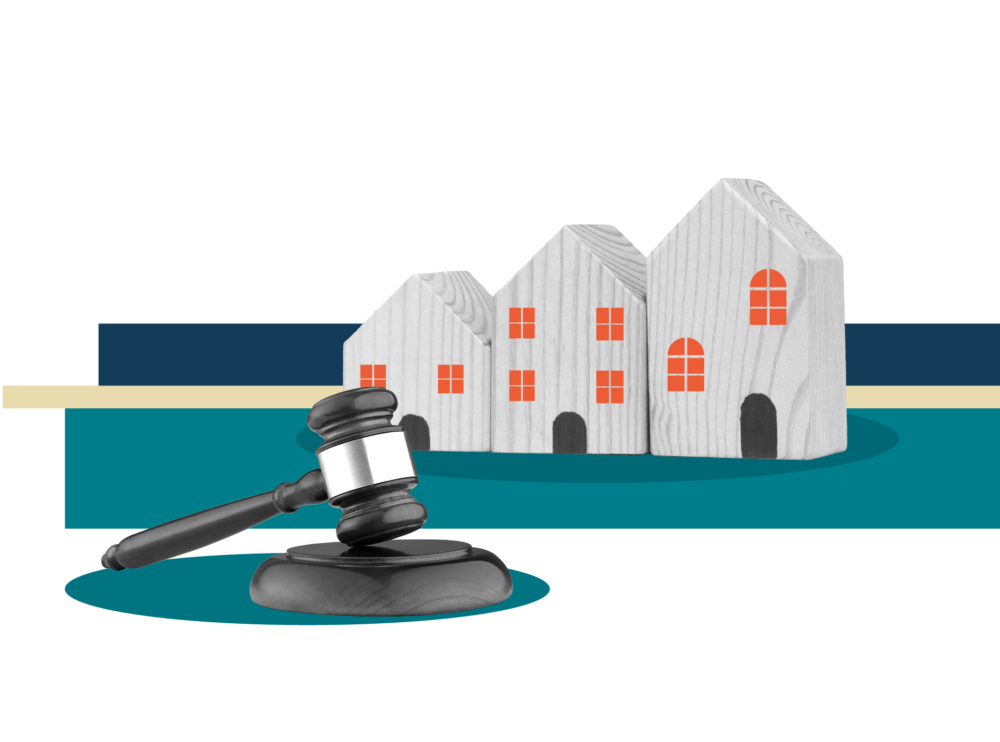 A legal gavel resting on a teal base in the foreground, with three wooden toy houses in the background set against a black backdrop with horizontal dark blue, cream, and teal stripes.